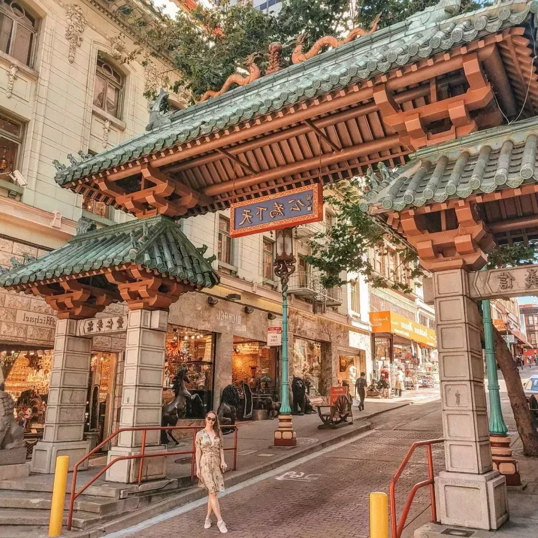 Una mujer posa frente a una puerta ornamentada que marca la entrada al Barrio Chino 贝博体彩app.